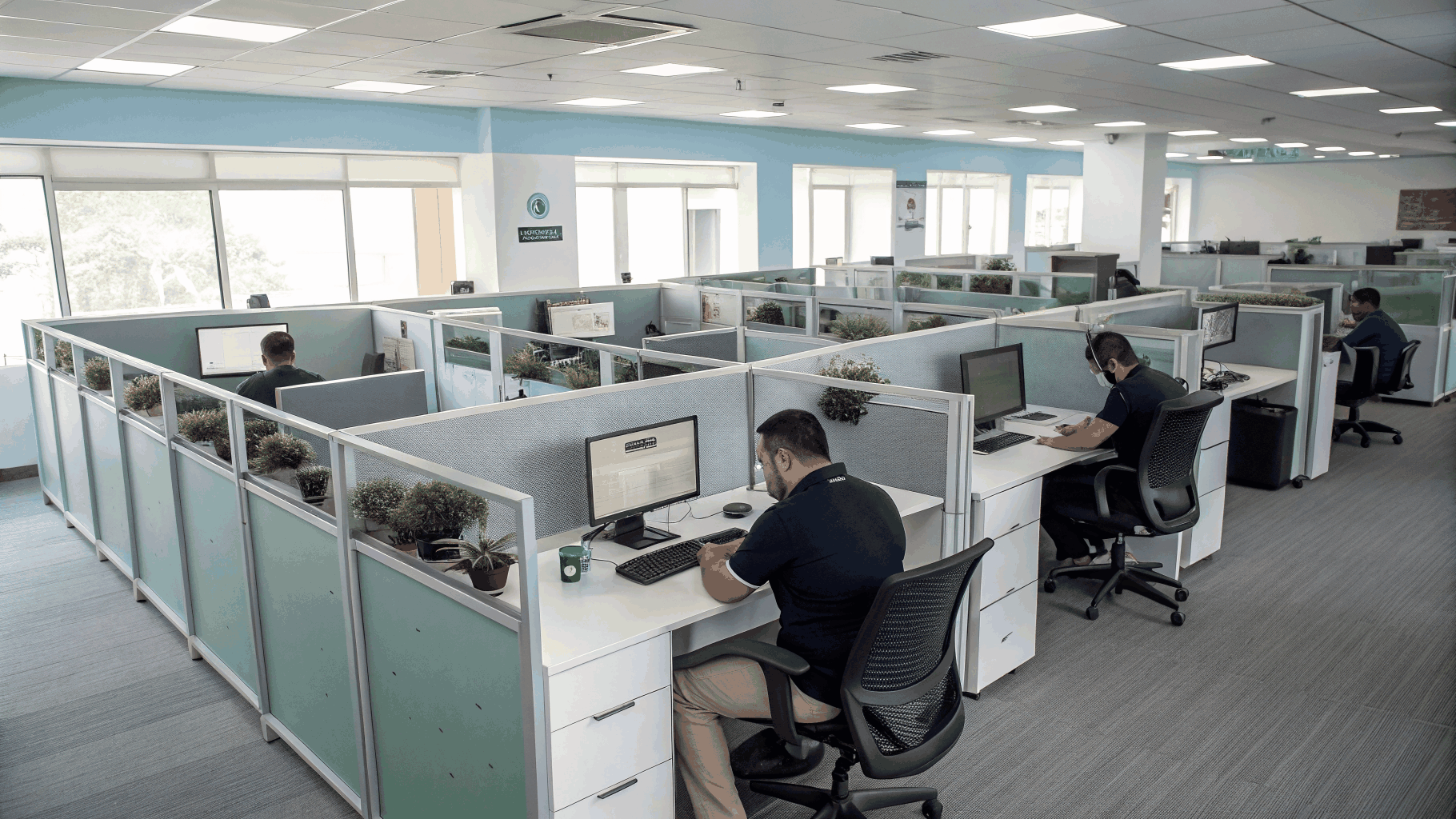 Diverse employees in business casual attire working naturally at individual desks in an authentic small business office